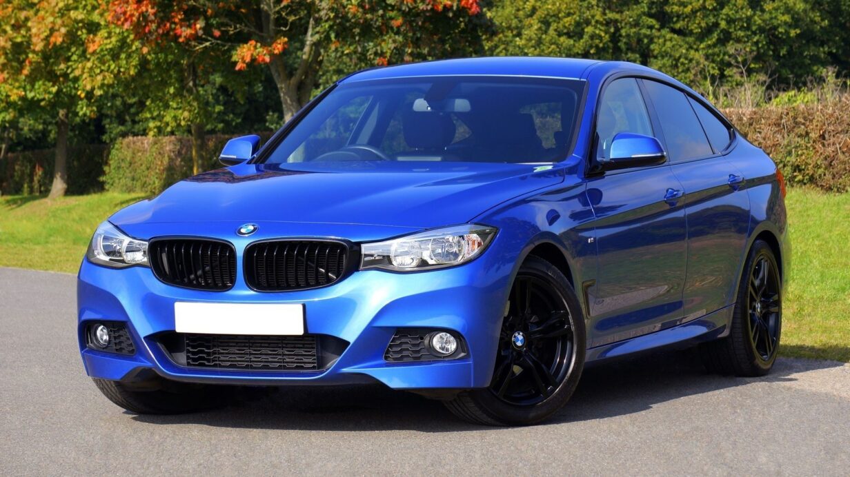 Blå BMW parkerad vid en väg i en grönskande miljö